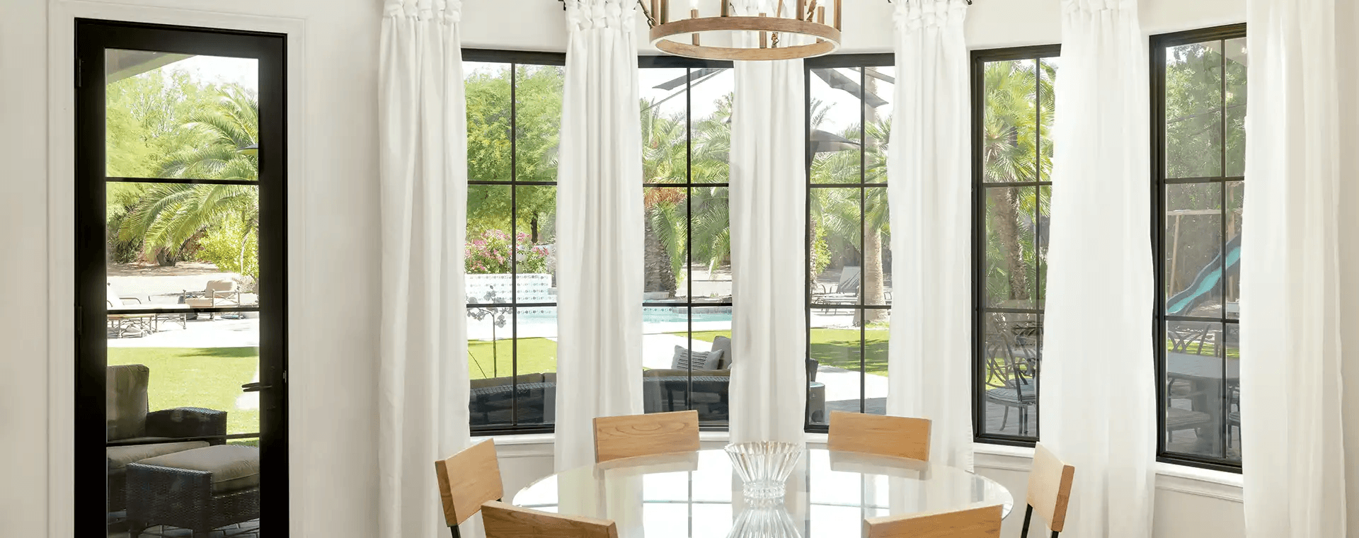 Black-trimmed bow windows in a dining area look out to a yard.